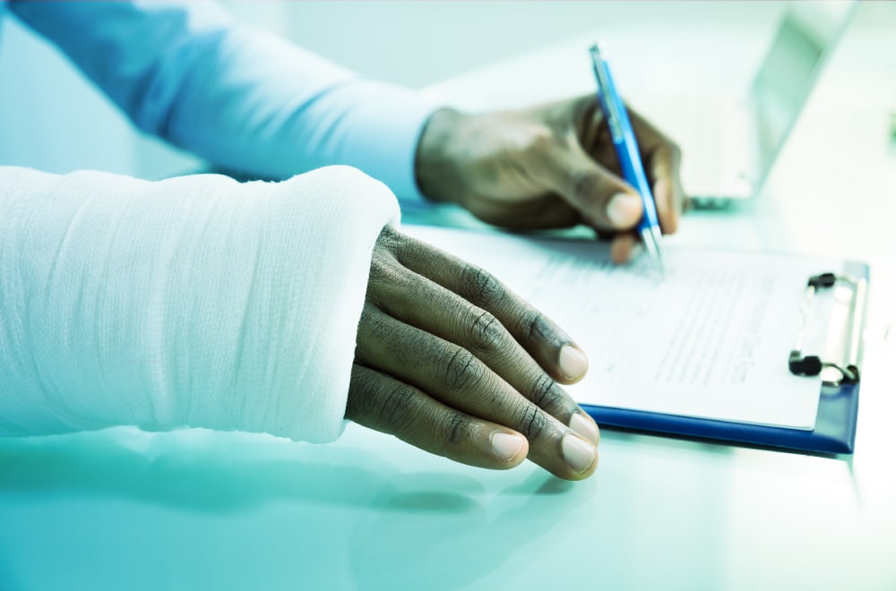 An person with a cast signs a legal form for a personal injury claim.