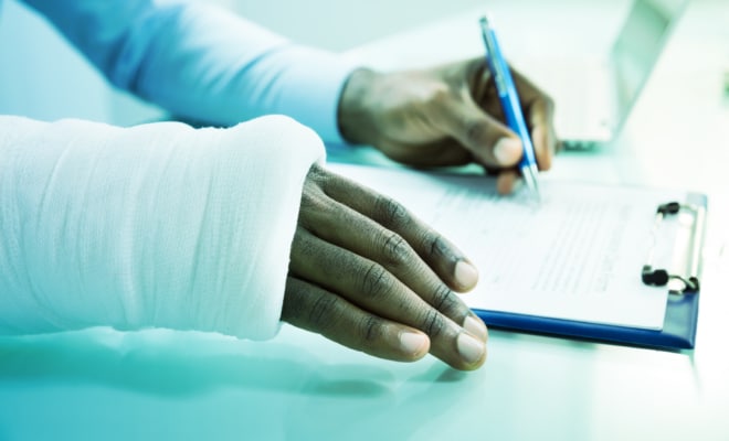An person with a cast signs a legal form for a personal injury claim.